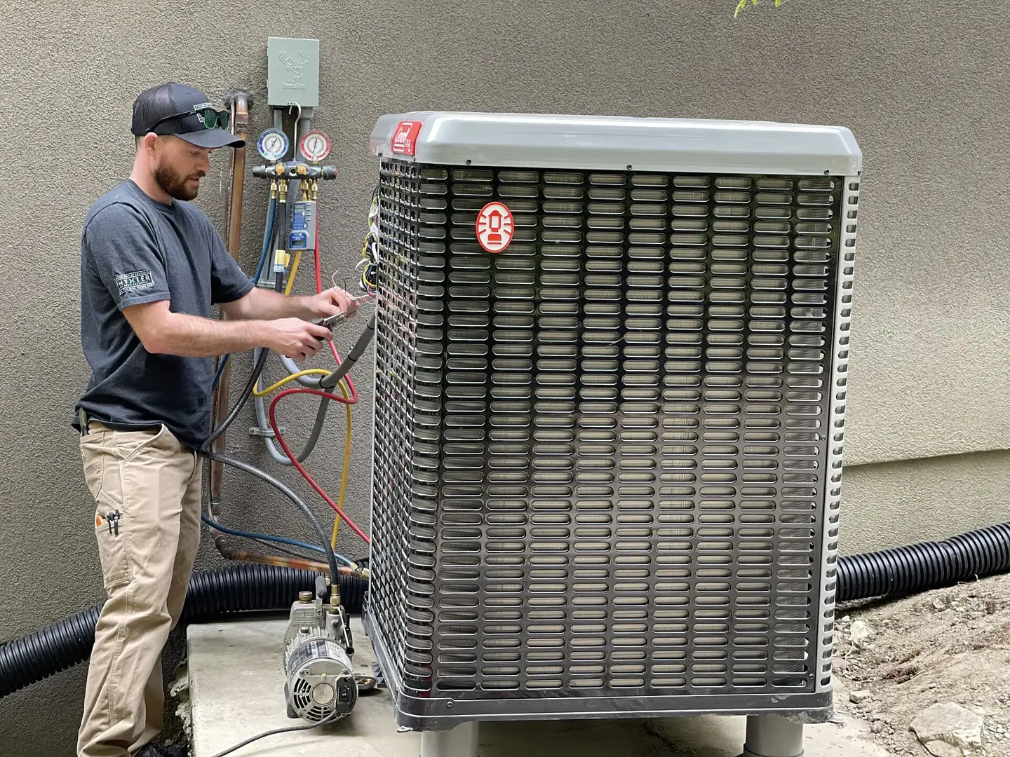 HVAC technician connecting gauges to a newly installed outdoor heat pump unit.