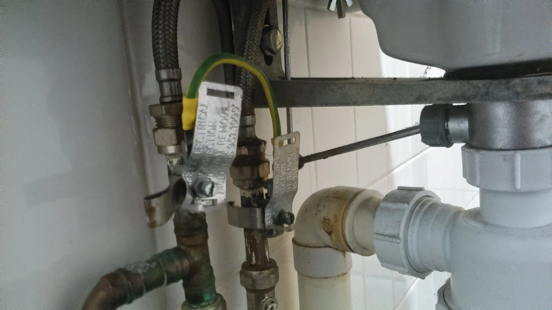 Supply lines and drain pipework underneath a kitchen sink.